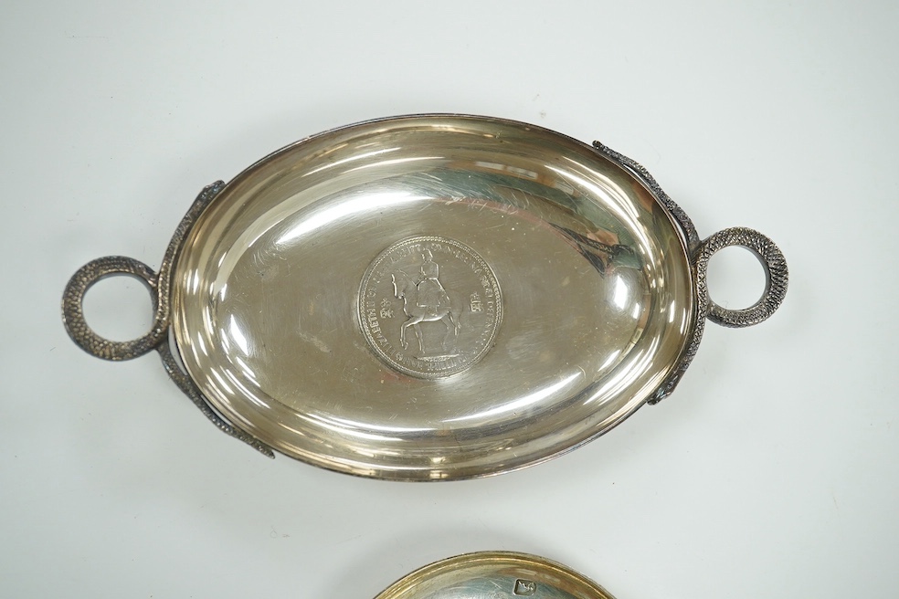 A 1970's Brittania standard silver commemorative small dish, C. Hoare & Co, London, 1972, 92mm, together with a German 925 oval dish with serpent handles and inset with coin, gross 8.9oz. Condition - fair